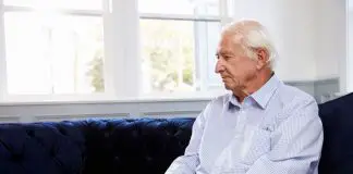 Depressed Senior Man Sitting On Sofa At Home