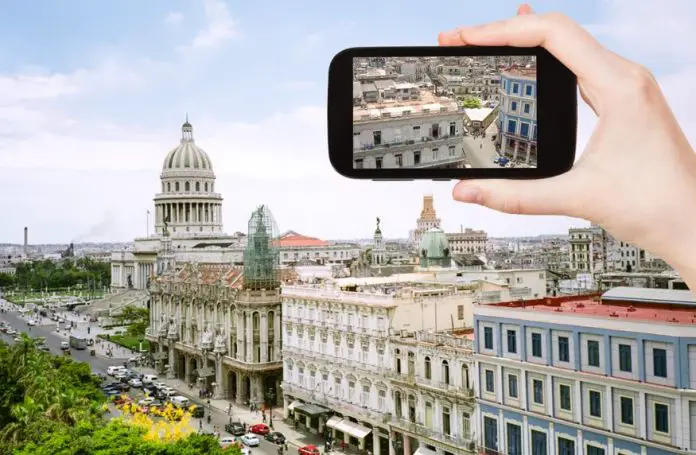 Tourist taking photo of the center of old Havana on mobile gadget.