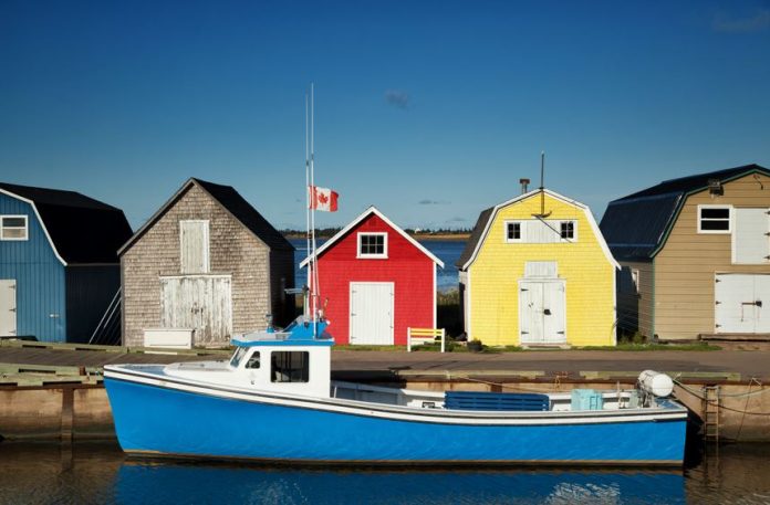 Blue fishing boat in front of oysters barns in New London, Prince Edward island also called PEI